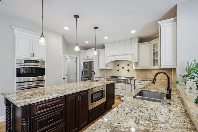 kitchen featuring stainless steel appliances, backsplash, hanging light fixtures, sink, and white cabinets