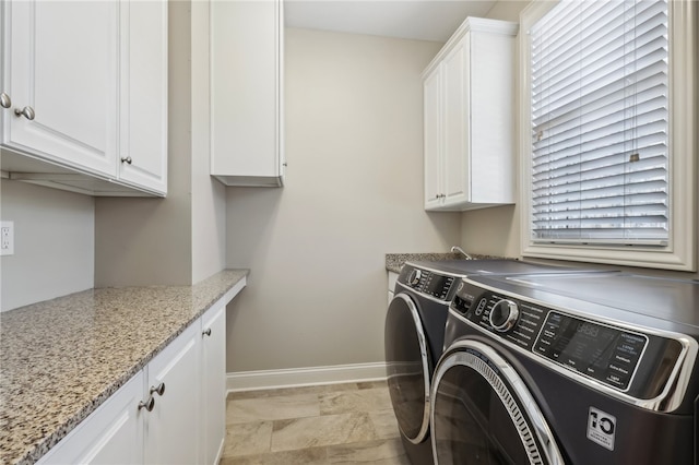 washroom with washer and clothes dryer, a wealth of natural light, and cabinets