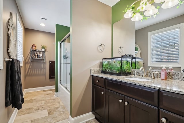 bathroom featuring vanity, bath / shower combo with glass door, and a healthy amount of sunlight