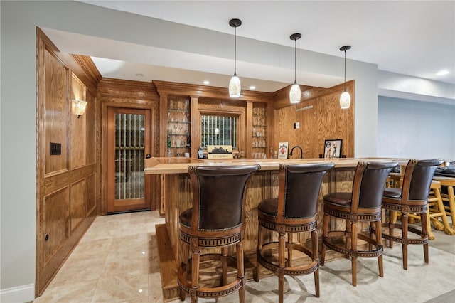 bar featuring hanging light fixtures and wooden walls