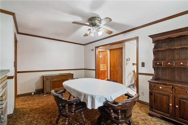 dining area featuring ceiling fan, crown molding, and dark carpet