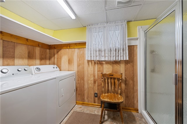 clothes washing area featuring wooden walls and washing machine and clothes dryer