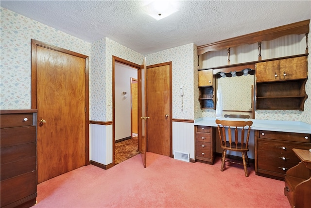 carpeted office space with a textured ceiling and built in desk