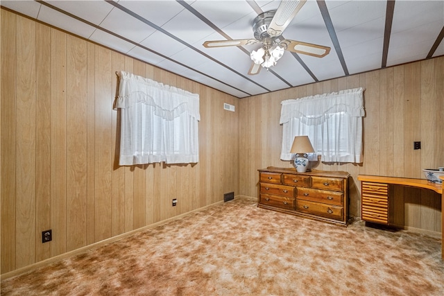 interior space featuring wood walls, ceiling fan, and carpet flooring