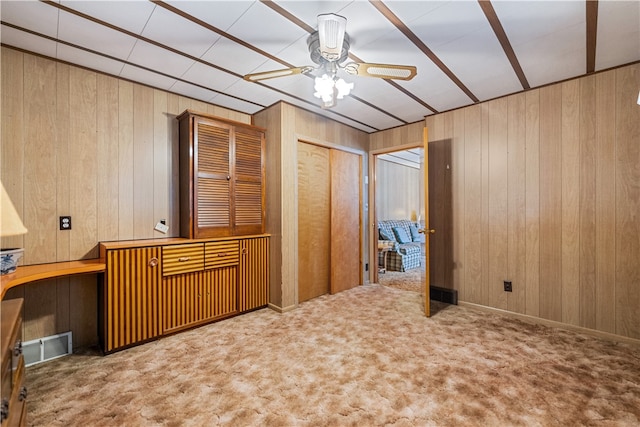 empty room featuring carpet, wooden walls, and ceiling fan