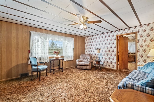 sitting room with carpet flooring, wood walls, and ceiling fan