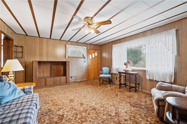 living room featuring carpet flooring, wooden walls, and ceiling fan