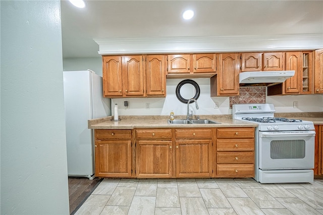 kitchen featuring sink, tasteful backsplash, crown molding, light wood-type flooring, and white appliances