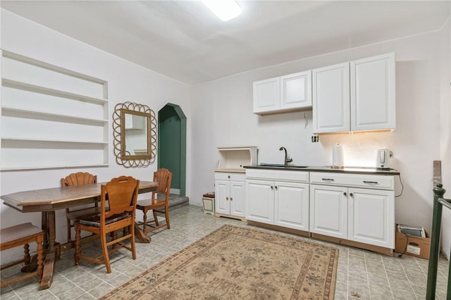 6824 Butler St, Morningside, PA 15206 - kitchen with a sink, arched walkways, white cabinets, and light flooring