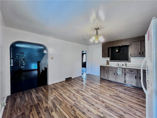 kitchen with an inviting chandelier, wood-type flooring, and dark brown cabinetry