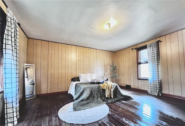 bedroom with dark hardwood / wood-style flooring and wooden walls