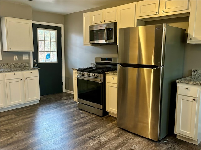 kitchen with white cabinets, appliances with stainless steel finishes, dark hardwood / wood-style floors, and light stone countertops