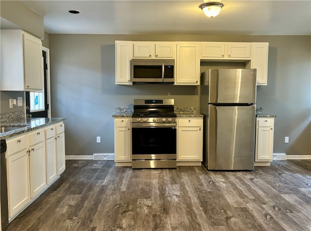 kitchen with stainless steel appliances, stone counters, white cabinets, and dark hardwood / wood-style flooring