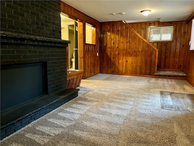 unfurnished living room with wood walls, a fireplace, and carpet flooring