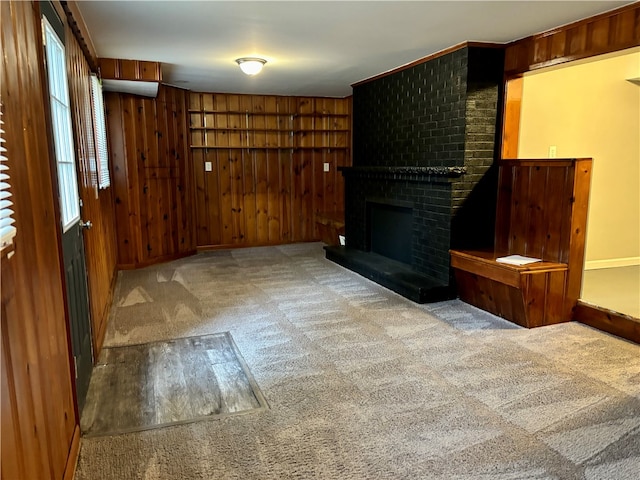 unfurnished living room with wood walls, a fireplace, and carpet