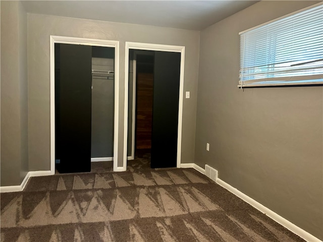 unfurnished bedroom with dark colored carpet and a closet