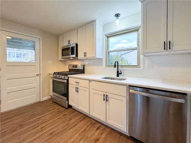 kitchen with white cabinetry, sink, light hardwood / wood-style flooring, and appliances with stainless steel finishes