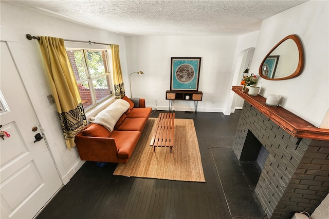 living room featuring a textured ceiling, dark hardwood / wood-style floors, and a fireplace