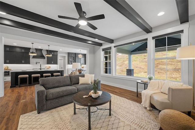 living room featuring dark hardwood / wood-style flooring, beamed ceiling, sink, and ceiling fan