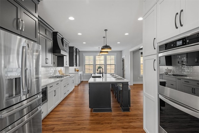 kitchen with decorative backsplash, appliances with stainless steel finishes, dark wood-type flooring, and an island with sink