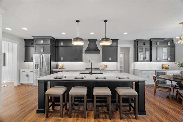 kitchen featuring hanging light fixtures, stainless steel appliances, dark wood-type flooring, and custom exhaust hood