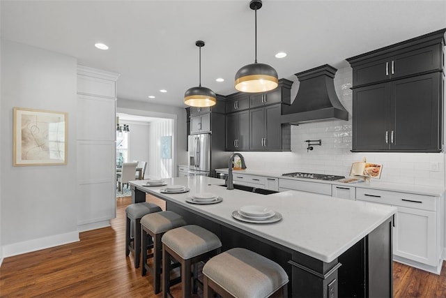 kitchen with white cabinets, a center island with sink, sink, and pendant lighting