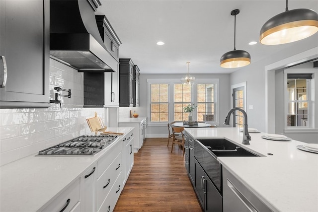 kitchen with white cabinetry, hanging light fixtures, decorative backsplash, dark wood-type flooring, and wall chimney exhaust hood