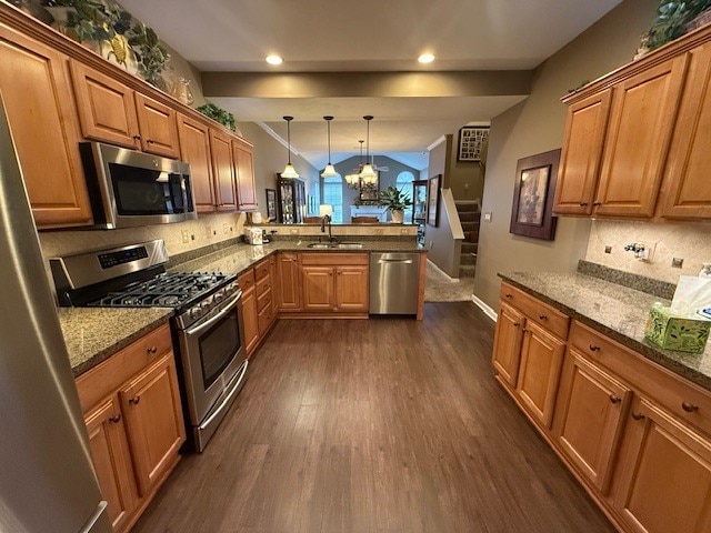 kitchen featuring sink, kitchen peninsula, appliances with stainless steel finishes, hanging light fixtures, and dark wood-type flooring