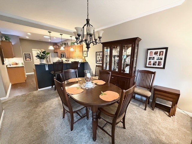 dining space with a chandelier, carpet flooring, and crown molding