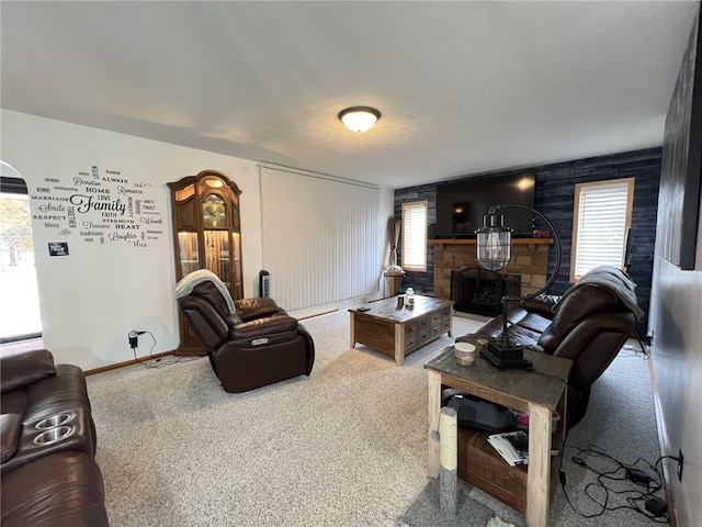 living room featuring a textured ceiling, a fireplace, a healthy amount of sunlight, and carpet flooring