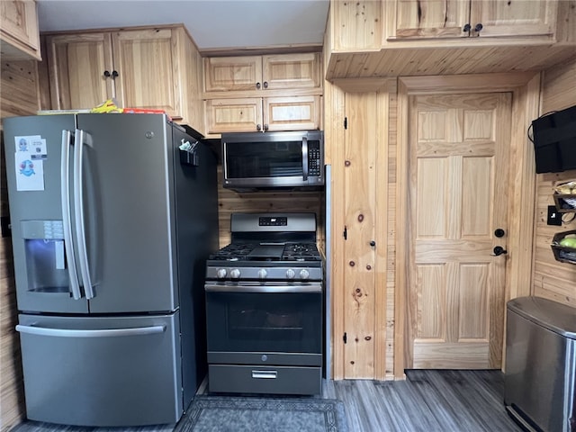 kitchen featuring dark wood-type flooring, wood walls, light brown cabinets, and appliances with stainless steel finishes