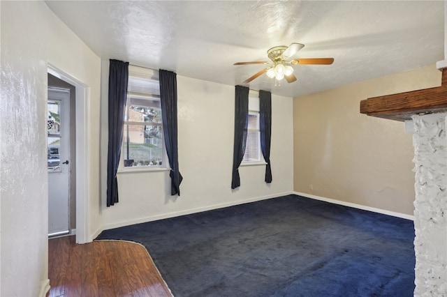 spare room with a textured ceiling, dark colored carpet, and ceiling fan