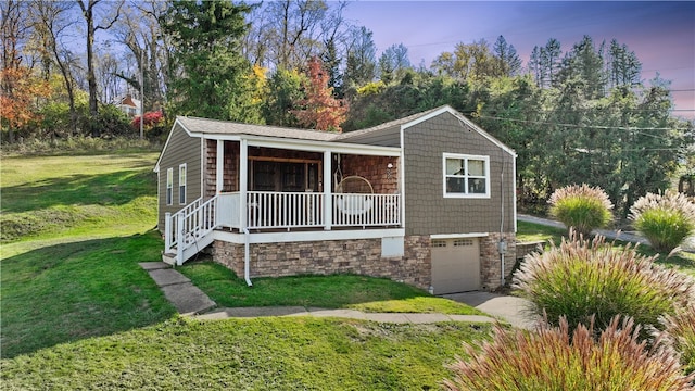 view of front of property with a garage, a lawn, and covered porch