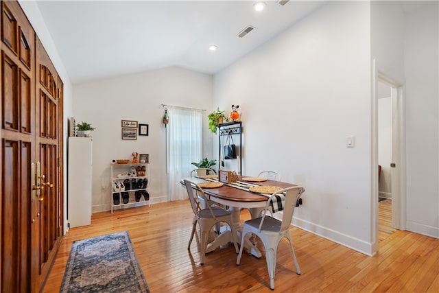 dining room featuring light wood-type flooring and vaulted ceiling