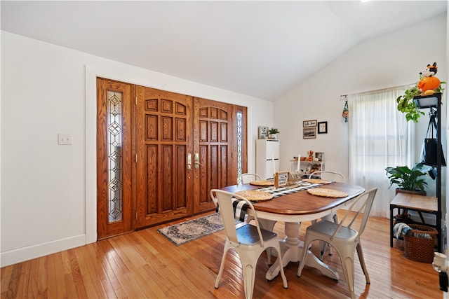 dining room with light hardwood / wood-style flooring and lofted ceiling