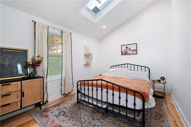 bedroom featuring hardwood / wood-style floors and lofted ceiling with skylight