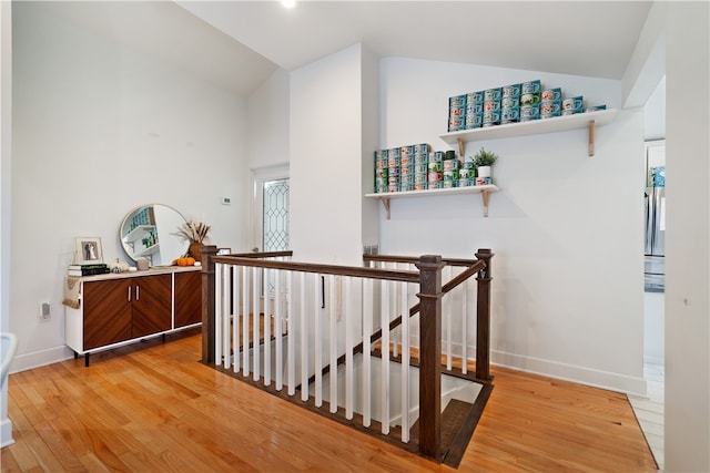 hallway featuring light wood-type flooring and vaulted ceiling