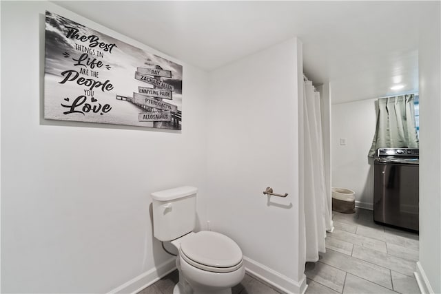 bathroom with tile patterned floors, toilet, and washer / dryer