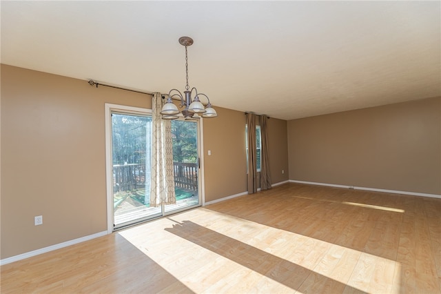 unfurnished dining area featuring an inviting chandelier and wood-type flooring