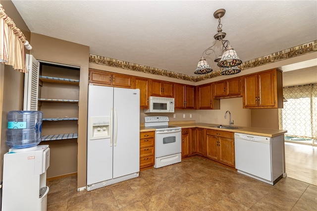 kitchen with sink, white appliances, decorative light fixtures, and a textured ceiling