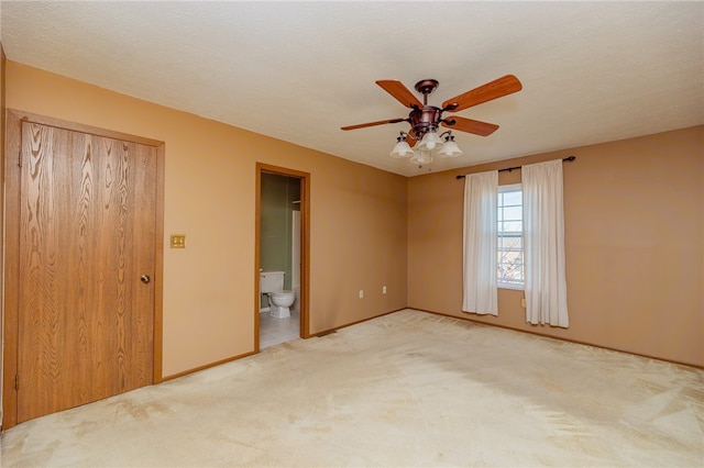 unfurnished bedroom with ensuite bathroom, ceiling fan, a textured ceiling, a closet, and carpet floors