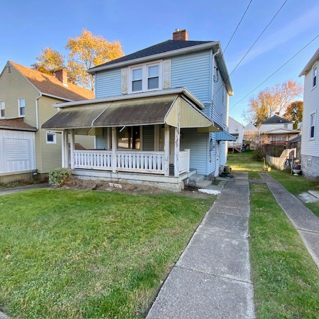 view of front of property with a storage unit, a front lawn, and covered porch