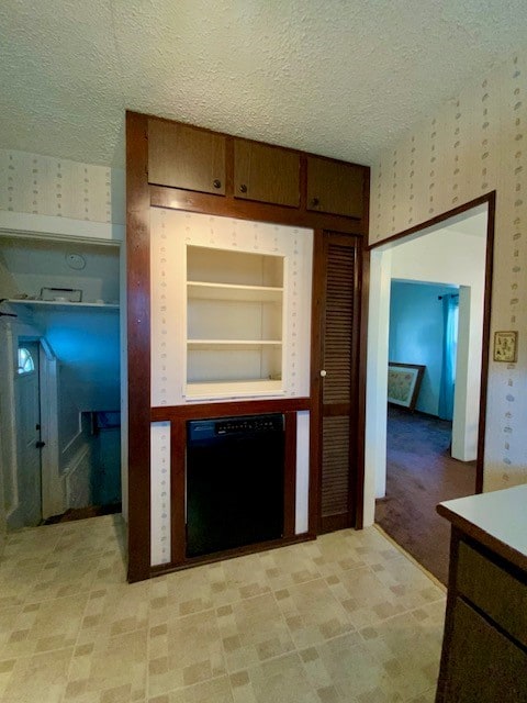 kitchen with black dishwasher, light colored carpet, a textured ceiling, and built in features