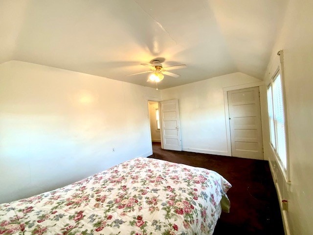 bedroom featuring vaulted ceiling, dark carpet, and ceiling fan