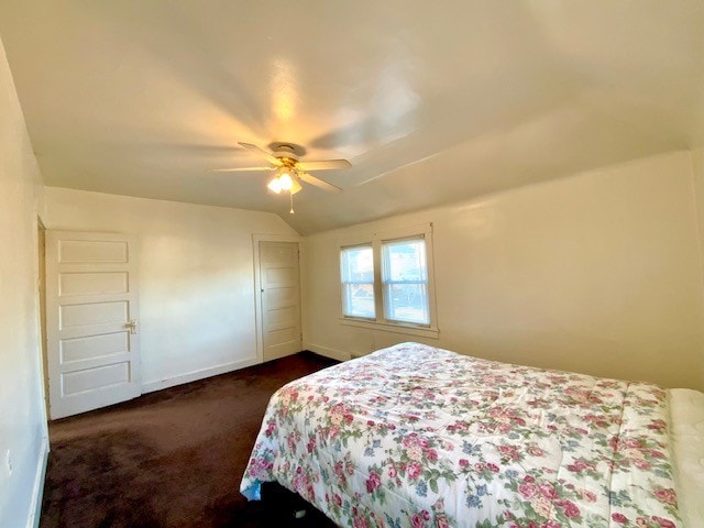 bedroom featuring dark colored carpet, lofted ceiling, and ceiling fan