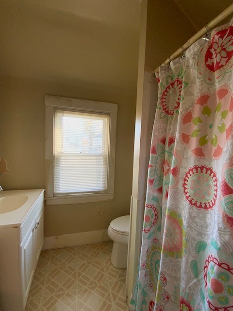 bathroom featuring walk in shower, vanity, tile patterned floors, and toilet