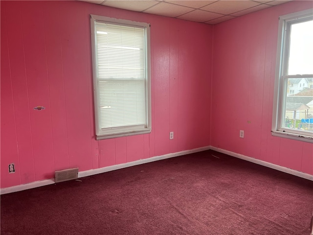 carpeted empty room featuring a paneled ceiling