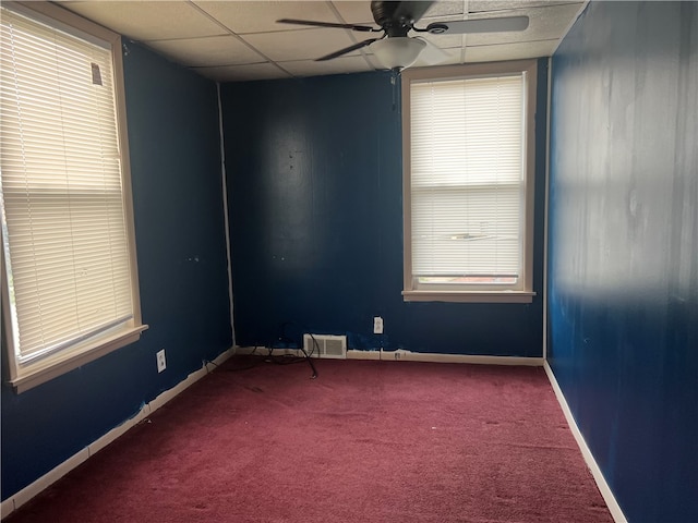 carpeted empty room featuring ceiling fan and a drop ceiling