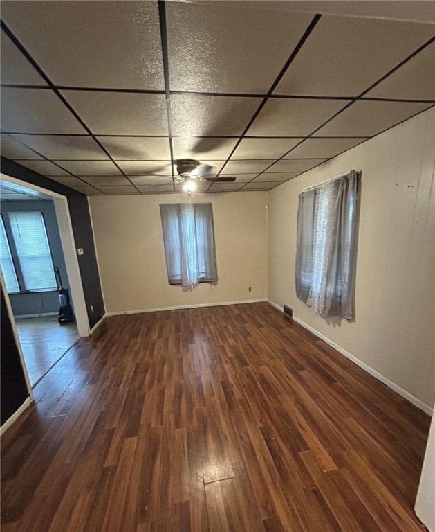 spare room featuring a drop ceiling, dark hardwood / wood-style floors, and ceiling fan