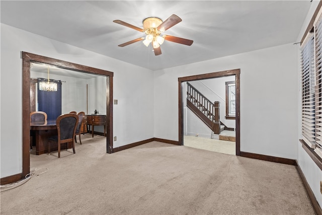 empty room featuring ceiling fan with notable chandelier and light carpet